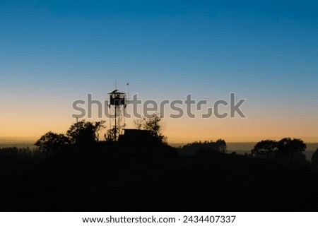 A silhouette of a watch tower against the rising sun.  Mapumalanga, South Africa. Royalty-Free Stock Photo #2434407337