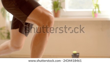 Strong male legs Close-up of knee joints. Strong Athletic Fit Man is Doing Fitness Exercises at Home. Strength training aimed at strengthening lower body, including thighs, glutes, and leg muscles.  Royalty-Free Stock Photo #2434418461