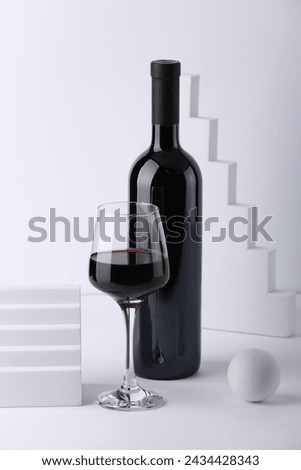 Stylish presentation of delicious red wine in bottle and glass on white background
