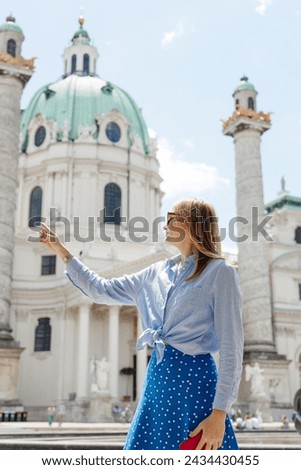 Young female tourist pointing finger near Catholic Church Karlskirche, Vienna. Saint Karl Cathedral. Traveling Europe in summer time. High quality photo