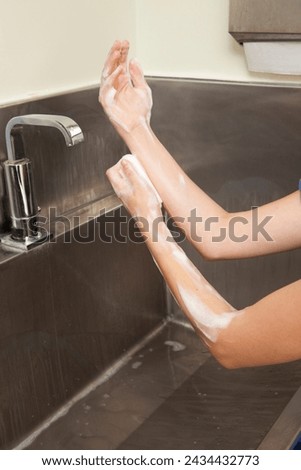 Surgeon having his hands surgically washed. A Caucasian doctor dressed in his right-hand profile with his hands full of foam and dressed in his surgical uniform.	 Royalty-Free Stock Photo #2434432773