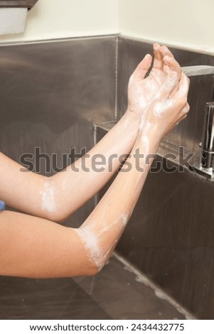 Surgeon having his hands surgically washed. A Caucasian doctor dressed in his right-hand profile with his hands full of foam and dressed in his surgical uniform.	 Royalty-Free Stock Photo #2434432775