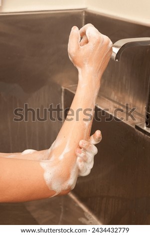 Surgeon having his hands surgically washed. A Caucasian doctor dressed in his right-hand profile with his hands full of foam and dressed in his surgical uniform.	 Royalty-Free Stock Photo #2434432779