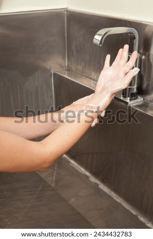 Surgeon having his hands surgically washed. A Caucasian doctor dressed in his right-hand profile with his hands full of foam and dressed in his surgical uniform.	 Royalty-Free Stock Photo #2434432783