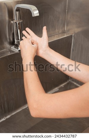 Surgeon having his hands surgically washed. A Caucasian doctor dressed in his right-hand profile with his hands full of foam and dressed in his surgical uniform.	 Royalty-Free Stock Photo #2434432787