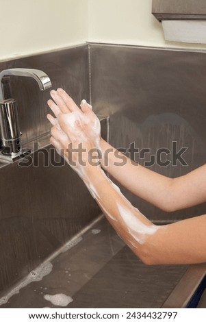 Surgeon having his hands surgically washed. A Caucasian doctor dressed in his right-hand profile with his hands full of foam and dressed in his surgical uniform.	 Royalty-Free Stock Photo #2434432797