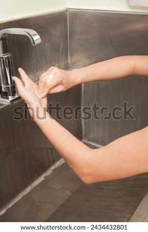 Surgeon having his hands surgically washed. A Caucasian doctor dressed in his right-hand profile with his hands full of foam and dressed in his surgical uniform.	 Royalty-Free Stock Photo #2434432801