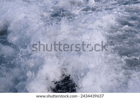 White foamy sea waves, strong swell, ship trail