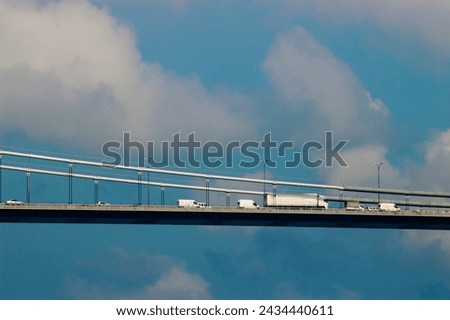 Fatih Bridge in Istanbul: Vehicles traverse under a serene blue sky with billowing clouds