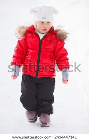 A little girl in a red and black winter outfit isolated on white backgroud. Vertical image. 