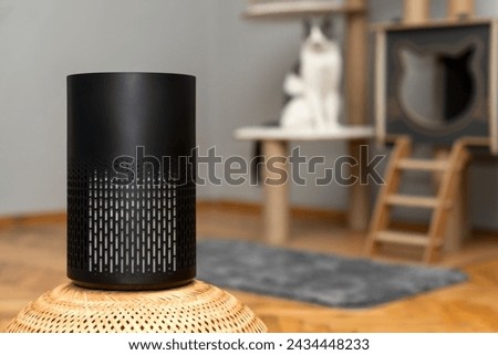 air purifier in the area with pets or cat. Air Pollution Concept. Air purifier, filters out invisible viruses, allergens or pollutants in the house on a cat tree background. Cute cat and Air purifier Royalty-Free Stock Photo #2434448233