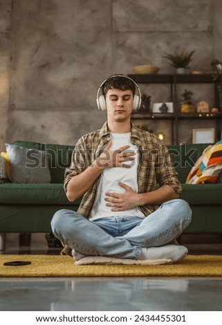 One teen man doing guided meditation yoga self care practice at home Royalty-Free Stock Photo #2434455301