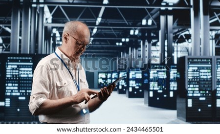 Senescent professional navigating network of server rigs in industrial nexus. Employee with tablet doing analysis and optimizations in high tech data center, preventing system perils Royalty-Free Stock Photo #2434465501