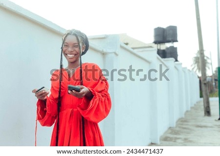 a free stock image of excited black african woman stands holding a mobile phone and credit card