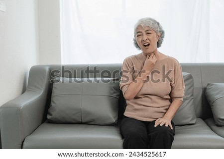 Hand touching throat, old man sore throat, coughing, hoarse voice, swelling, Asian elderly woman suffering from throat problems, tonsillitis, painful swallowing Royalty-Free Stock Photo #2434525617