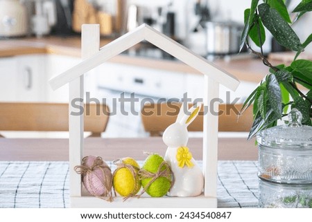 Tiny house of cozy home with Easter decor with rabbit and eggs on table of kitchen. Building, design, project, moving to new house, mortgage, insurance, rent and purchase real estate