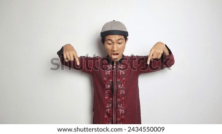 shocked asian muslim man gesturing pointing down on white background