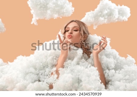 Young woman with white clouds blowing on beige background