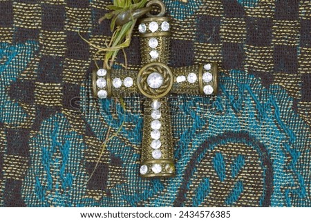 An ornamental cross on a blue,colorful woven cloth.
