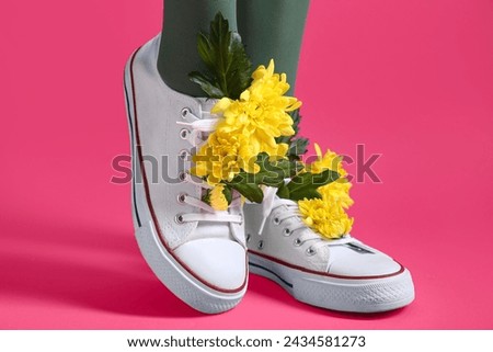 Legs of beautiful young woman in white gumshoes with yellow chrysanthemum flowers on pink background Royalty-Free Stock Photo #2434581273