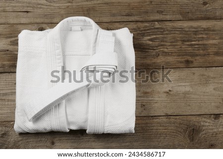 White karate belt and kimono on wooden background, top view. Space for text Royalty-Free Stock Photo #2434586717