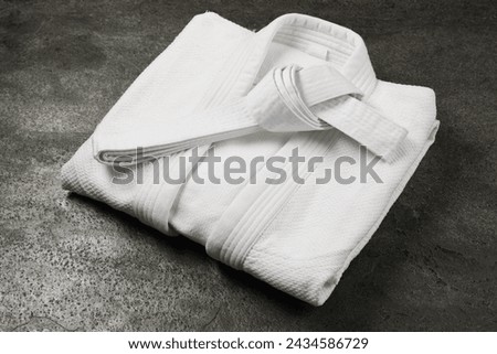 White karate belt and kimono on gray textured background Royalty-Free Stock Photo #2434586729