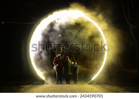Illuminated portal with fog and smoke in the middle of the road. Silhouettes of people in the middle of the portal