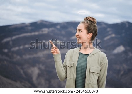 Young positive smiling woman pointing her fingers at empty space aside for your text, girl points with index finger at blank copy space for promotional content, demonstrates interesting product