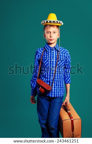 Funny little child traveler with vintage camera, sombrero and suitcase. Travel and vacation concept.