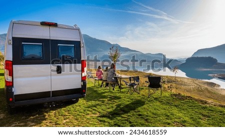Campervan, Motorhome RV parked next to the lake or river in Bosnia and Herzegovina. Family with camper van or motor home eating breakfast on an active family vacation on a road trip to Ramsko lake. Royalty-Free Stock Photo #2434618559