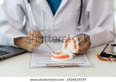 female dentist Denture model, tooth simulator and survey mirror tool for showing and explaining to patients at clinic office, dental health care concept.