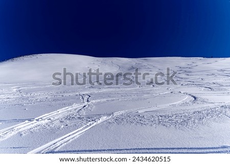 Looking up snow covered hill with ski tracks at Klingenstock mountain at Stoos on a sunny winter day. Photo taken February 13th, 2024, Klingenstock, Stoos, Canton Schwyz, Switzerland.