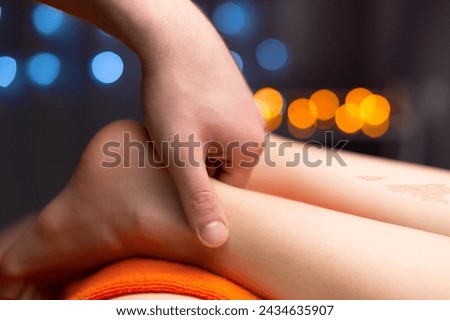 Close-up in shallow depth of field of a male masseur's hands massaging the Achilles tendon of a female leg. Professional massage in a professional room Royalty-Free Stock Photo #2434635907