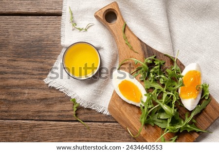 Close-up of rucolla, boiled egg and olive oil on a wooden board. Healthy vegetarian breakfast. Top view Royalty-Free Stock Photo #2434640553