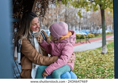 Looking down, the happy little girl, snug in winter clothes, shares laughter with her parents, creating a delightful moment of family warmth during their walk. 