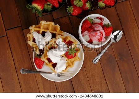 Strawberry ice cream sundae and waffles with whipped cream and strawberries viewed from above