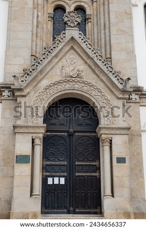 Entrance portal in carved stone with pantocrator iconography with closed doors of Our Lady of help church, Espinho PORTUGAL Royalty-Free Stock Photo #2434656337