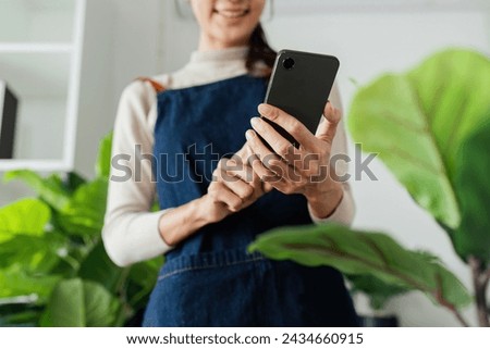 woman hold mobile and take picture of newly plant tree. eco friendly home