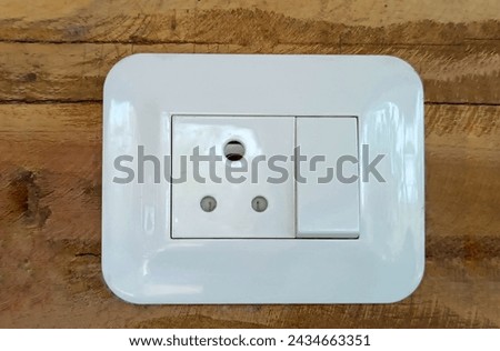 Sleek white plug-in with switch board on wooden backdrop - minimalist efficiency meets rustic charm. 