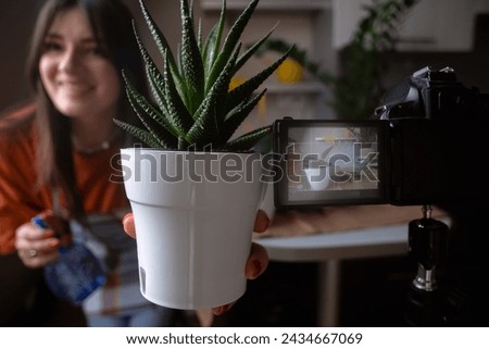 Girl filming blog on camera while replanting flowers Lifestyle blogger gardening at home. Trend content for social media and vlogs