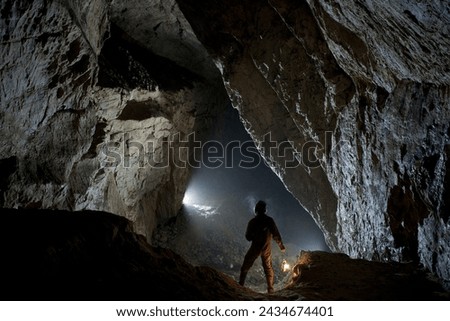 A speleologist poses in a massive karst cave corridor.