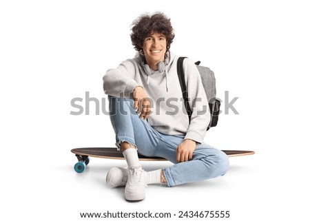 Happy young man sitting on a skateboard isolated on white background