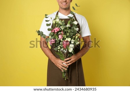 Florist with beautiful bouquet on yellow background, closeup
