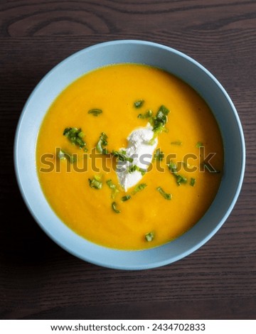 delicious carrot soup in a bowl with cream and green onion close-up