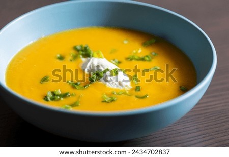 delicious carrot soup in a bowl with cream and green onion close-up