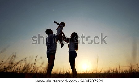 family standing on field. happy childhood concept for little child. big happy family stands on field, parents raised the lifestyle child in their arms, sunset on the background, silhouettes Royalty-Free Stock Photo #2434707291