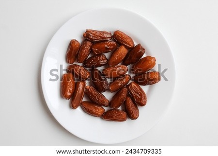 Deglet noor or deglet nour or date palm or dates, in a transparent white plate, isolated on white background, flat lay or top view Royalty-Free Stock Photo #2434709335