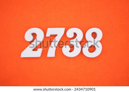 Orange felt is the background. The numbers 2738 are made from white painted wood. Royalty-Free Stock Photo #2434710901