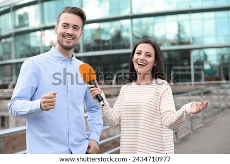 Young journalist interviewing man on city street Royalty-Free Stock Photo #2434710977