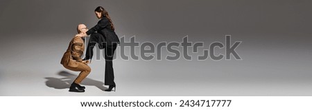 brunette woman balancing in high heels while stepping on hand of dancing partner in suit, banner